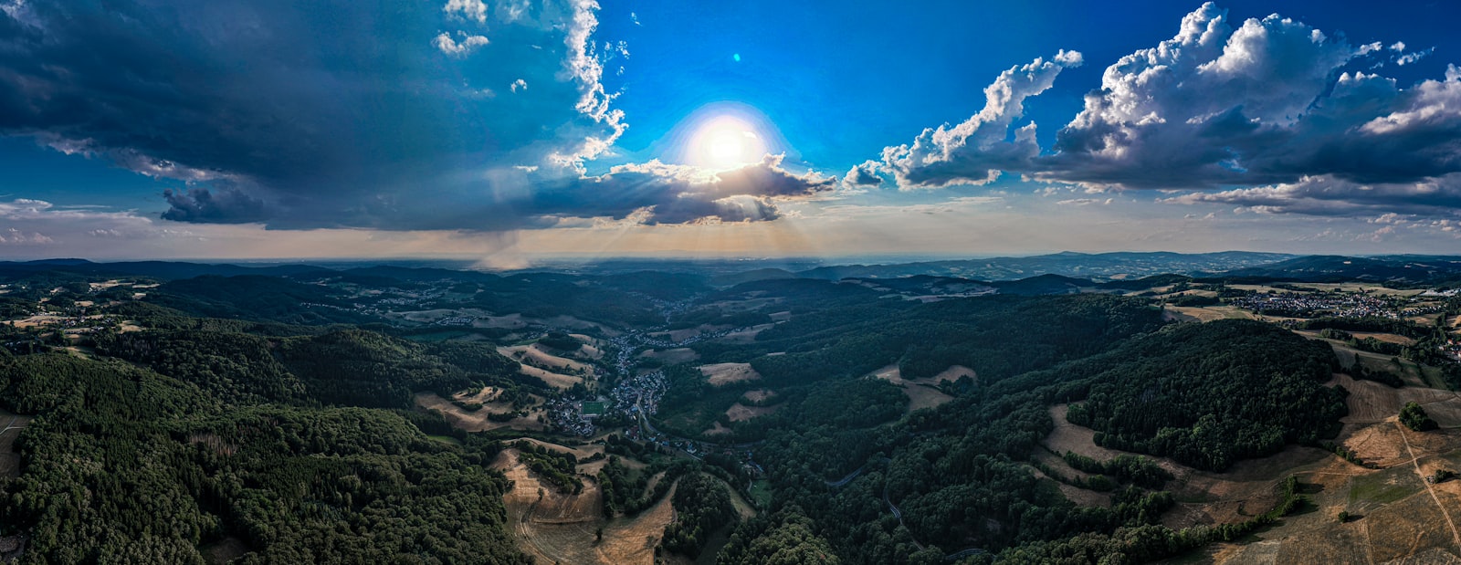 Expansive green hills under a bright sun, representing environmental care