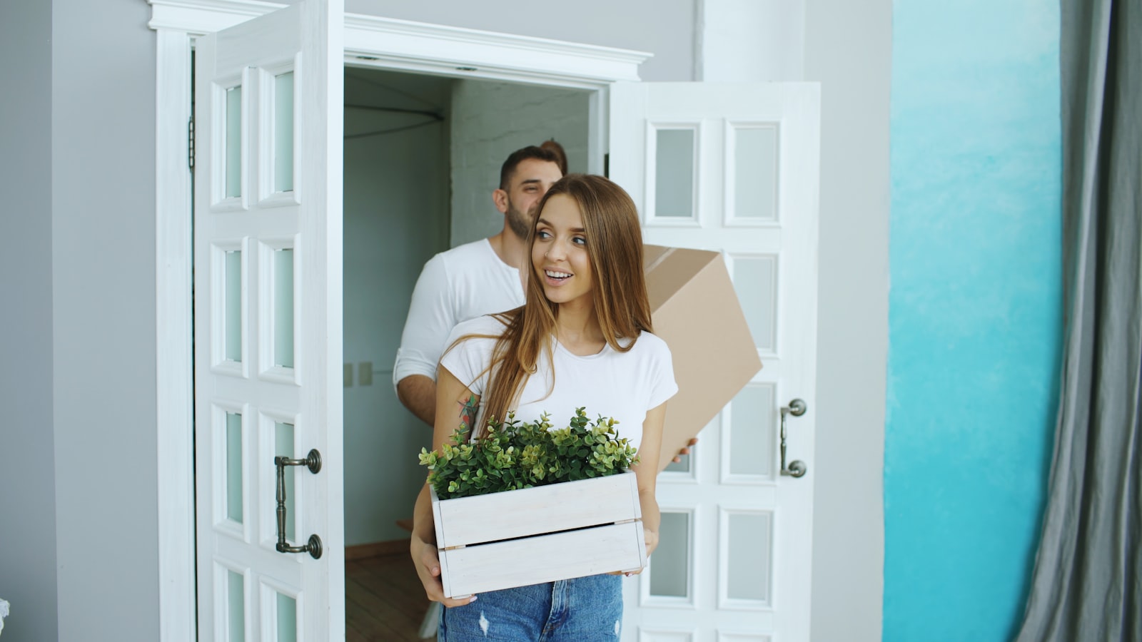 Couple carrying moving boxes into a new home