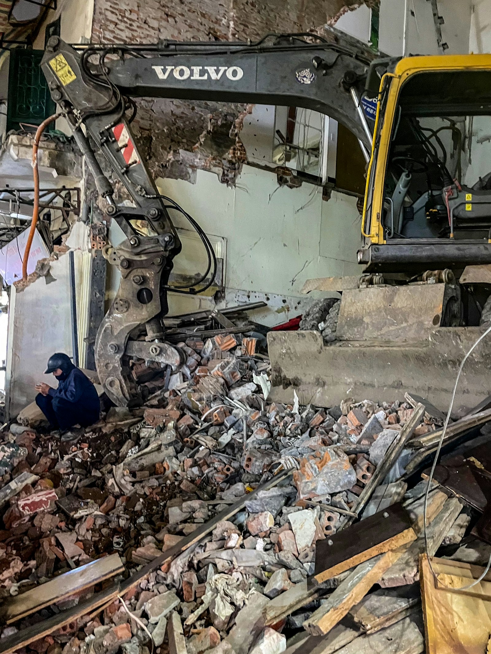 Excavator clearing building rubble and debris at a demolition site